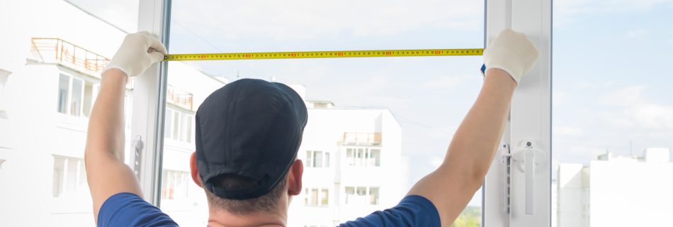 vitrier mesure une vitre à l'aide d'un mètre